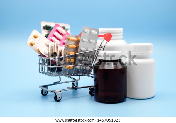  Concepto de medicina. Varias cápsulas, envase de medicinas en el carrito de la tienda con botellas de medicina en un fondo azul, concepto de Pills, Comprar y comprar medicina.