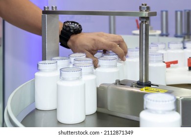 Medicine Or Cosmetic White Plastic Bottle On The Production Line Of The Conveyor Belt At Filling Machine In The Healthcare Manufacturing.
