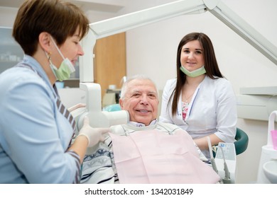 Medicine, Dentistry And Healthcare Concept - Female Dentist With X-ray Machine Scanning Senior Man Patient Teeth At Dental Clinic. Radiography Procedure And Dental Care For Older People. 