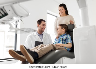 Medicine, Dentistry And Healthcare Concept - Mother And Son Visiting Dentist At Dental Clinic