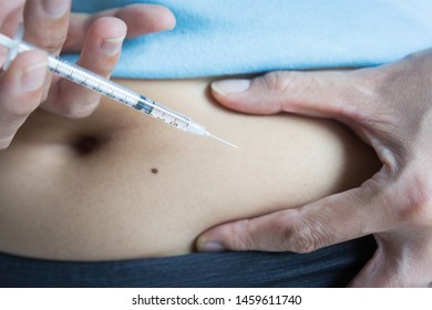 Medicine for diabetes disease of health care and self-care concept. Close-up of woman with syringe making insulin injections at abdominal skin (intra subcutaneous) for hyperglycemia by herself.