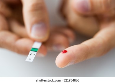 Medicina, diabetes, glicemia, atención de la salud y concepto de personas - cierre del dedo macho con gota de sangre y tira de prueba