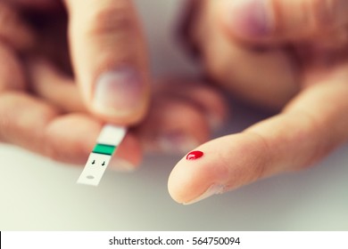 Medicine, Diabetes, Glycemia, Health Care And People Concept - Close Up Of Male Finger With Blood Drop And Test Stripe