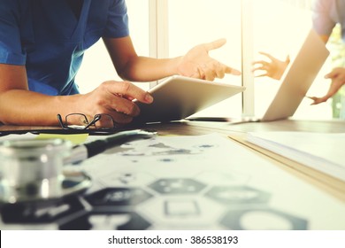 Medicine doctor hand working with modern computer and digital tablet computer and medical diagram with his team on wooden desk as medical concept                                - Shutterstock ID 386538193