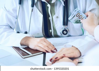 Medicine Doctor Receiving Large Amount Of Dollar Banknotes As A Bribe. Corruption In Health Care Industry Concept.