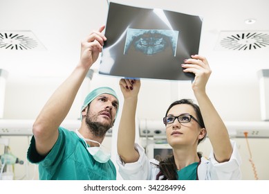 Medicine doctor showing something to her male colleague on x-ray image. Healthcare and medical concept - Powered by Shutterstock