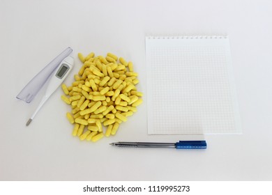 Medicine, drugs, health – a lot of yellow capsules next to the white digital thermometer and paper for the label handle (copy space) - Shutterstock ID 1119995273