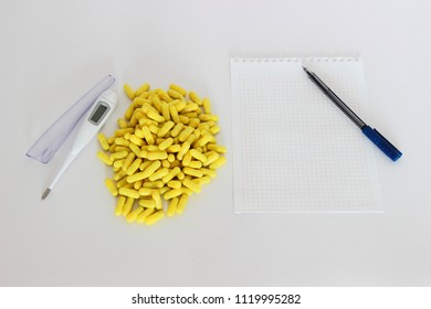 Medicine, drugs, health – a lot of yellow capsules next to the white digital thermometer and paper for the label handle (copy space) - Shutterstock ID 1119995282