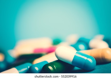 Medicine green and yellow pills or capsules on blue background with copy space. Drug prescription for treatment medication. Pharmaceutical medicament, cure in container for health. Antibiotic