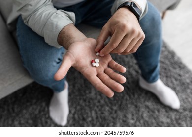 Medicine in hand. Patient committing suicide by overdosing on medication. Close up of overdose pills and addict. Sad unhappy millennial european man holding many different drugs on palm, top view