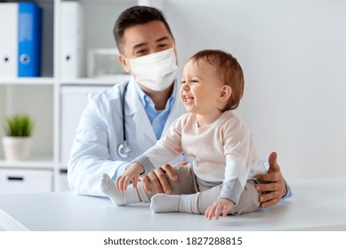 medicina, atención de la salud, pediatría y concepto de personas - médico feliz o pediatra que lleva máscara protectora facial para la protección contra la enfermedad por virus con el bebé en un examen médico en la clínica