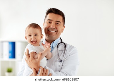 medicine, healtcare, pediatry and people concept - happy doctor or pediatrician holding baby on medical exam at clinic