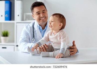 medicine, healtcare, pediatry and people concept - happy doctor or pediatrician holding baby on medical exam at clinic