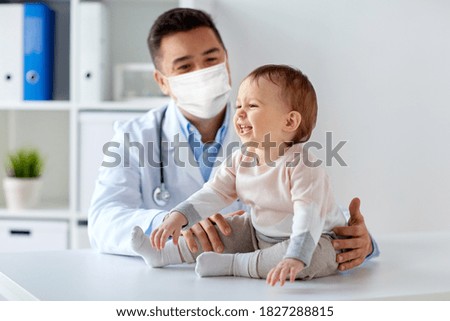 medicine, healtcare, pediatry and people concept - happy doctor or pediatrician wearing face protective mask for protection from virus disease with baby on medical exam at clinic