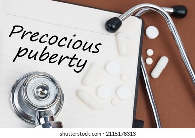 Medicine and health concept. On a brown surface lie pills, a stethoscope and a notebook with the inscription - Precocious puberty