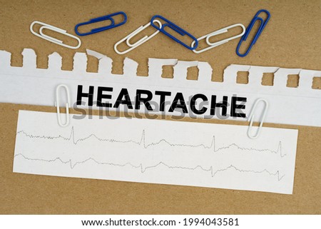 Medicine and health concept. On the table lies a cardiogram, paper clips and paper with the inscription - heartache
