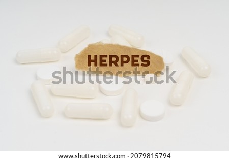 Medicine and health concept. On a white background pills and a piece of paper with the inscription - HERPES