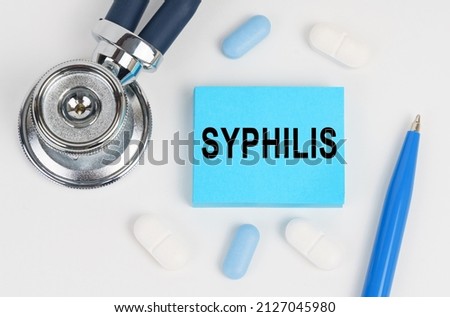 Medicine and health concept. On a white surface lie pills, a stethoscope and stickers with the inscription - Syphilis