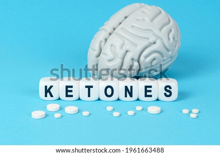 Medicine and health. Cubes lie on the table among the pills and imitation of the brain. The text on the dice - KETONES