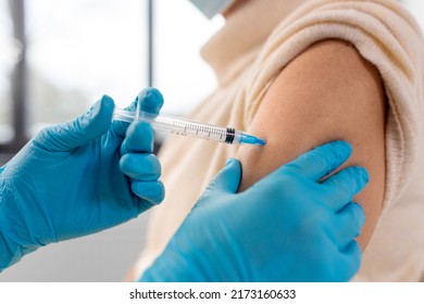 medicine, health and vaccination concept - close up of doctor or nurse with syringe making vaccine or drug injection to woman at hospital - Shutterstock ID 2173160633