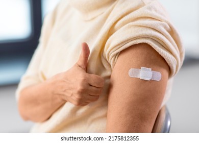 Medicine, Health And Vaccination Concept - Close Up Of Vaccinated Senior Woman In Mask With Medical Patch On Arm Showing Thumbs Up At Hospital