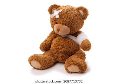 medicine, healthcare and childhood concept - teddy bear toy with bandaged paw and patch on head on white background