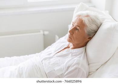 Medicine, Healthcare And Old People Concept - Sad Senior Woman Lying On Bed At Hospital Ward