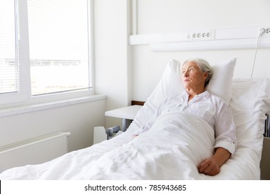 Medicine, Healthcare And Old People Concept - Sad Senior Woman Lying On Bed At Hospital Ward