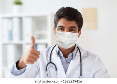 Medicine, Healthcare And Pandemic Concept - Indian Male Doctor With Stethoscope Wearing Protective Medical Mask For Protection From Virus Showing Thumbs Up At Clinic