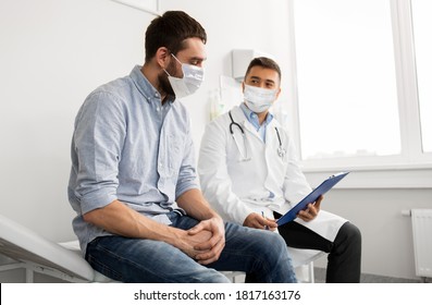 Medicine, Healthcare And Pandemic Concept - Male Doctor Wearing Face Protective Medical Mask For Protection From Virus Disease With Clipboard And Young Man Patient Meeting At Hospital