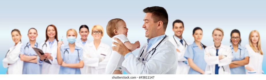 medicine, healthcare, pediatry and people concept - happy doctor or pediatrician holding baby on medical exam over blue background
