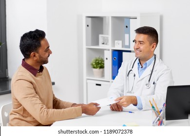 Medicine, Healthcare And People Concept - Doctor Giving Prescription To Male Patient At Clinic