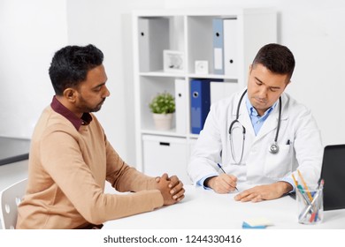 Medicine, Healthcare And People Concept - Doctor Writing Prescription For Male Patient At Clinic