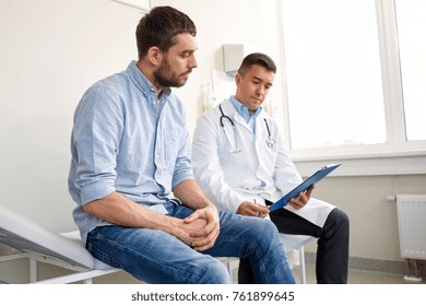 Medicine, Healthcare And People Concept - Doctor With Clipboard And Young Male Patient Having Health Problem Meeting At Hospital