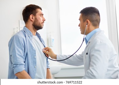 Medicine, Healthcare And People Concept - Doctor With Stethoscope Checking Patient Heart Beat Or Breath At Hospital