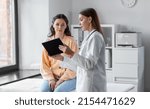medicine, healthcare and people concept - female doctor with tablet pc computer talking to woman patient at hospital