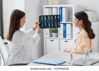 medicine, healthcare and people concept - female doctor or vertebrologist showing x-ray image of spine to woman patient at hospital - Shutterstock ID 2159944235