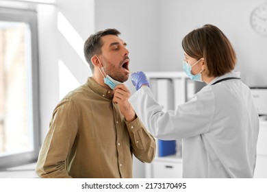Konzept Medizin, Gesundheitsversorgung und Menschen - Ärztin in Maske mit Zungendepressor oder Kontrolle der Halsschmerzen eines Krankenhauspatienten