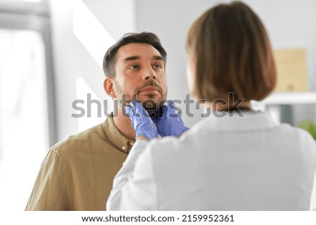 medicine, healthcare and people concept - female doctor checking lymph nodes of man patient at hospital