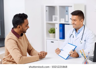 Medicine, Healthcare And People Concept - Happy Doctor With Cardiogram And Young Male Patient Meeting At Hospital