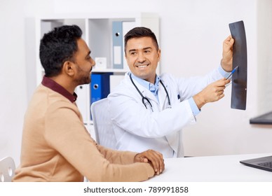 Medicine, Healthcare And People Concept - Happy Doctor Or Surgeon Showing X-ray To Male Patient At Clinic