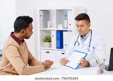 Medicine, Healthcare And People Concept - Happy Doctor With Cardiogram And Young Male Patient Meeting At Hospital