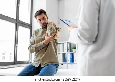 Medicine, Healthcare And People Concept - Male Patient Showing Sore Arm To Female Doctor At Medical Office In Hospital