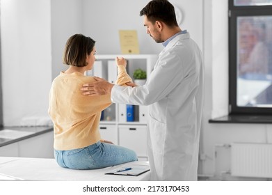 medicine, healthcare and people concept - male doctor with clipboard talking to woman showing her sore arm patient at hospital