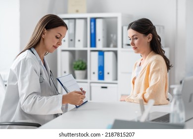 Medicine, Healthcare And People Concept - Smiling Female Doctor Or Cardiologist With Clipboard Showing Cardiogram To Woman Patient At Hospital