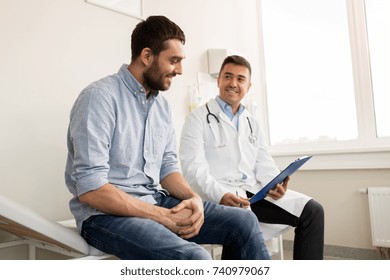 medicine, healthcare and people concept - smiling doctor with clipboard and young man patient meeting at hospital - Shutterstock ID 740979067