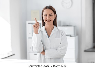 medicine, healthcare and profession concept - smiling female doctor pointing finger up at hospital - Powered by Shutterstock