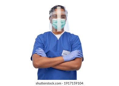 Medicine, Healthcare And Protection Concept - Indian Doctor Or Male Nurse In Blue Uniform, Protective Medical Mask And Face Shield Over White Background