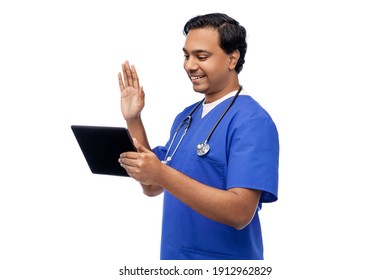 Medicine, Healthcare And Technology Concept - Happy Smiling Indian Doctor Or Male Nurse In Blue Uniform With Stethoscope Having Video Call On Tablet Pc Computer Over White Background