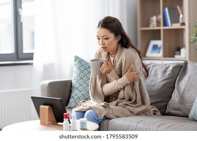 Medicine, Healthcare And Technology Concept - Sick Young Asian Woman Having Video Call Or Online Consultation On Tablet Pc Computer And Drinking Tea At Home